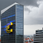 **

Prompt: "Modern commercial real estate exterior, interest rate graph overlay, euro symbols, emphasizing financial challenges, overcast sky, realistic."

**